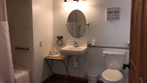 A bathroom with a toilet, sink, mirror, and a towel rack.