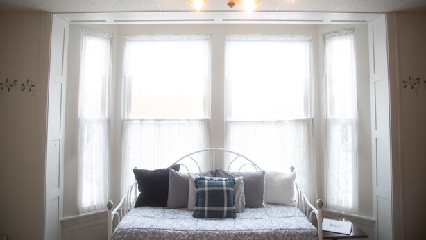 Ein Schlafzimmer mit einem Bett, einer Kandelaber und einem Fenster mit Vorhängen.