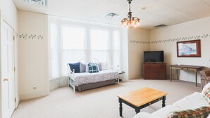 Ein gemütliches Wohnzimmer mit einer Couch, einem Holztisch, einem Fernseher und einem gerahmten Bild an der Wand.