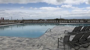 Une piscine avec des chaises longues et une terrasse carrelée.