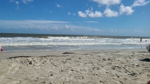 Une plage avec un rivage sablonneux, des vagues et un ciel dégagé.