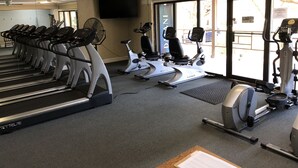 Une salle de sport équipée de tapis de course, de vélos d’appartement et d’appareils de musculation elliptique.
