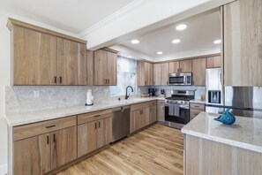 Une cuisine moderne avec des meubles en bois, des appareils en acier inoxydable et un plan de travail en marbre.