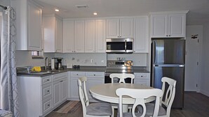 Una cocina moderna con armarios blancos, electrodomésticos de acero inoxidable y una mesa redonda con cuatro sillas.