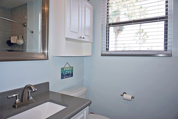 A bathroom with a sink, toilet, and window with blinds.