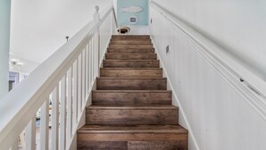 Un escalier en bois avec des rampes blanches et un mur bleu clair orné d’un motif de poisson.