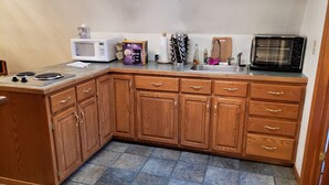 A compact kitchen with wooden cabinets, a microwave, a coffee maker, and a sink.