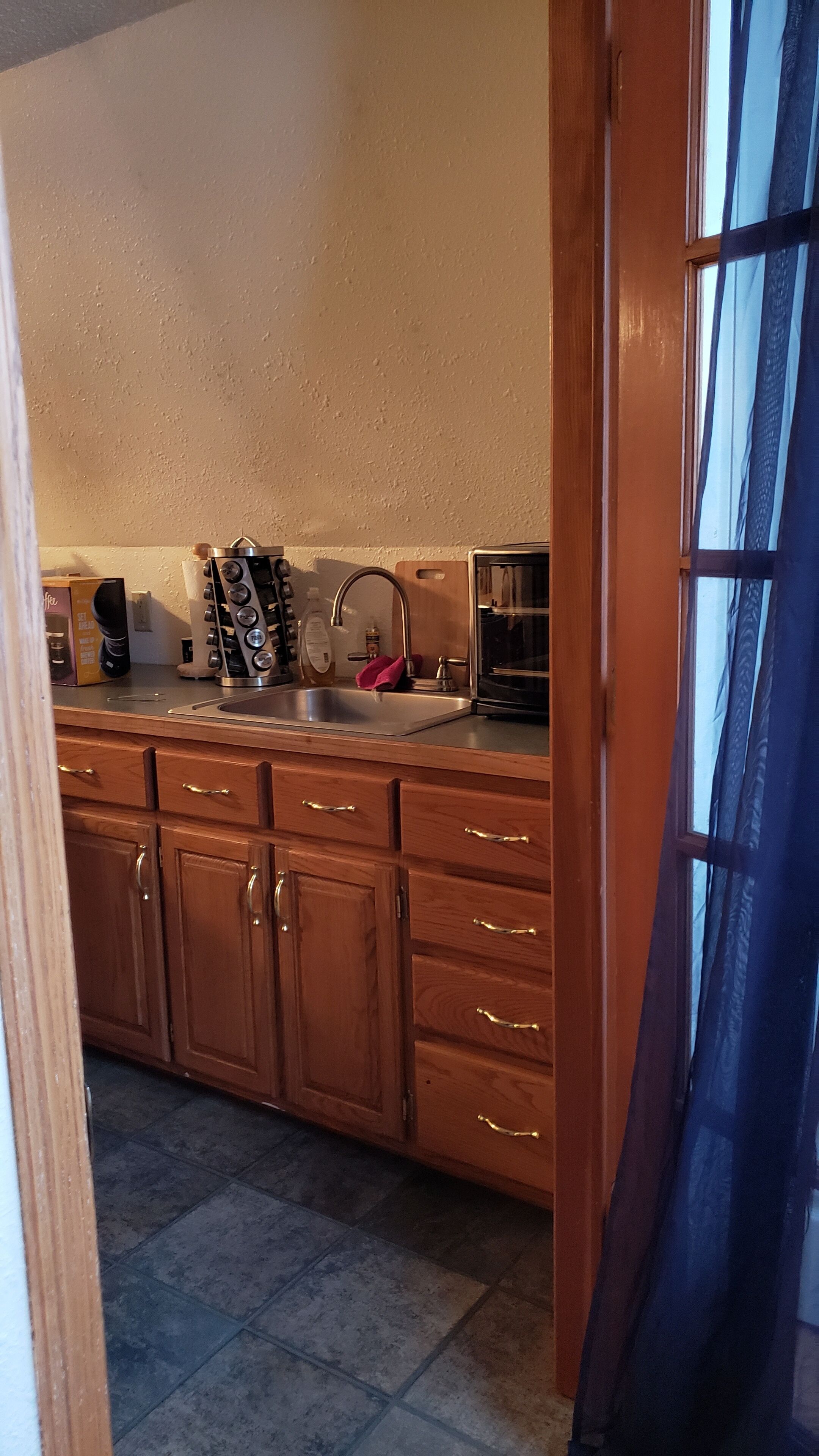 A kitchen with wooden cabinets, a stainless steel sink, and a coffee maker.