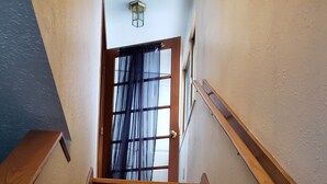 A staircase with wooden handrails and carpeted steps leading to an open door with a view of the outside.