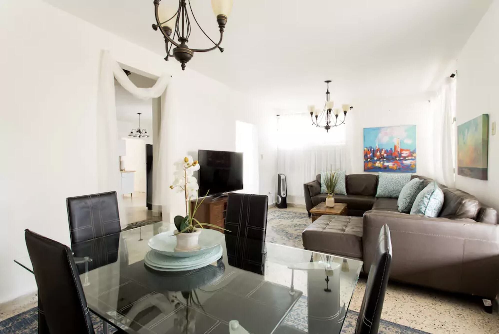 Una sala de estar moderna con una mesa de comedor de vidrio, sofás de cuero y una televisión.