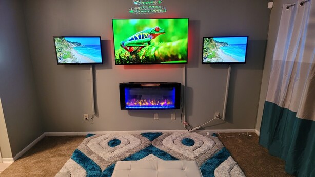 Una sala de estar con una televisión de pantalla plana montada en la pared, una chimenea debajo y un tapete estampado.