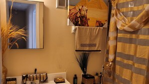 Un baño con lavamanos, espejo, tocador, inodoro y cortina de ducha.