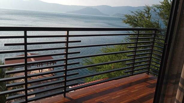Un balcon offrant une vue sur une étendue d’eau et sur des montagnes lointaines.
