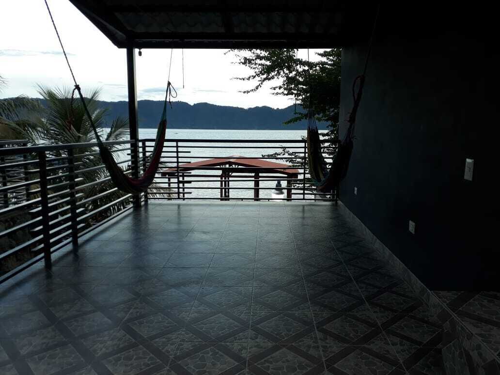 Un espacio interior con vista al mar, una hamaca y una zona de estar techada.