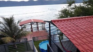 Un espace piscine agrémenté d’une structure surmontée d’un toit rouge, d’une petite piscine et d’une vue sur la mer.