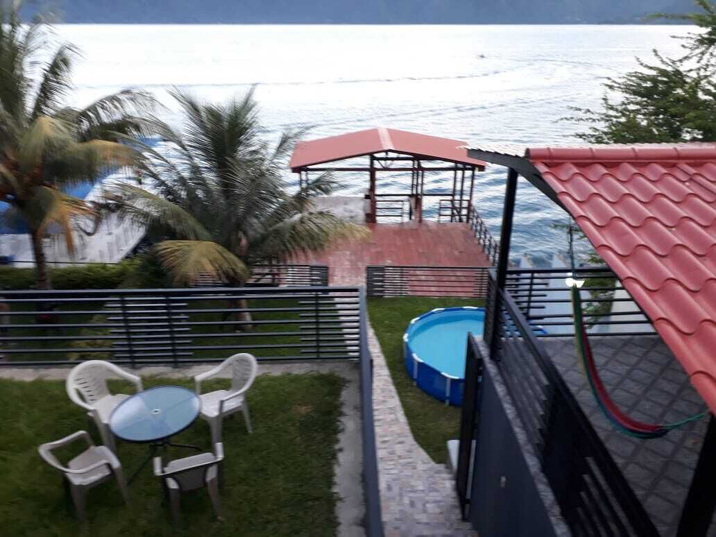 A patio area with a pool, a covered seating area, and a view of the sea.
