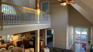 A spacious loft with a high ceiling, a dining area, a living room with a sofa, and a view of a dock.