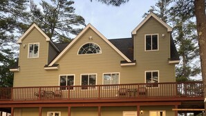 A two-story house with a balcony, a front door, and a deck leading to the entrance.
