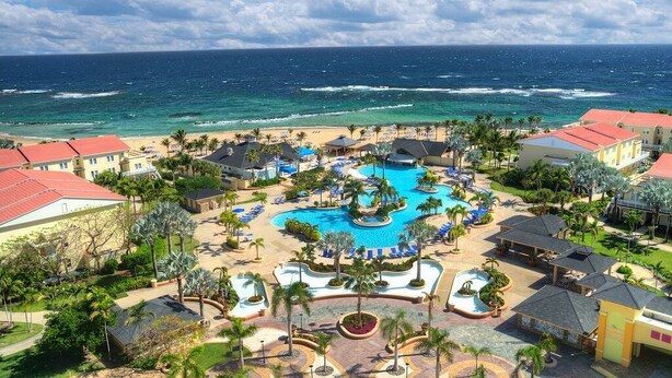 Ett semesterhotell med en central pool, tillgång till stranden och utsikt över havet.