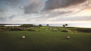 En golfbana med utsikt över havet och molnen på himlen.