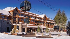 A multi-story hotel with a ski lift, stone pillars, and snow-covered surroundings.