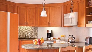 A kitchen with wooden cabinets, a granite countertop, a built-in sink, a microwave, a kettle, and a toaster.