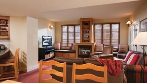 A living room with a fireplace, wooden furniture, and a television.