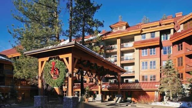 A multi-story building with a covered entrance, stone pillars, and a wooden facade.