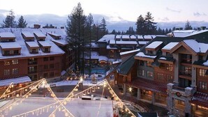 A resort with multiple buildings, some with snow-covered roofs, and a central area with lights.