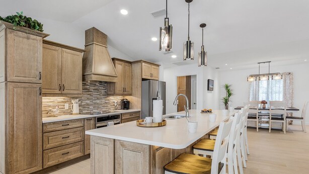 A modern kitchen with wooden cabinets, a central island, and pendant lighting. - Amazing water views, heated pool & spa, Tiki & kayaks -Villa SeaOarNo - Roelens Vacations (Cape Coral)
