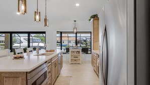 A modern kitchen with a large island, stainless steel appliances, and pendant lighting. - Amazing water views, heated pool & spa, Tiki & kayaks -Villa SeaOarNo - Roelens Vacations (Cape Coral)