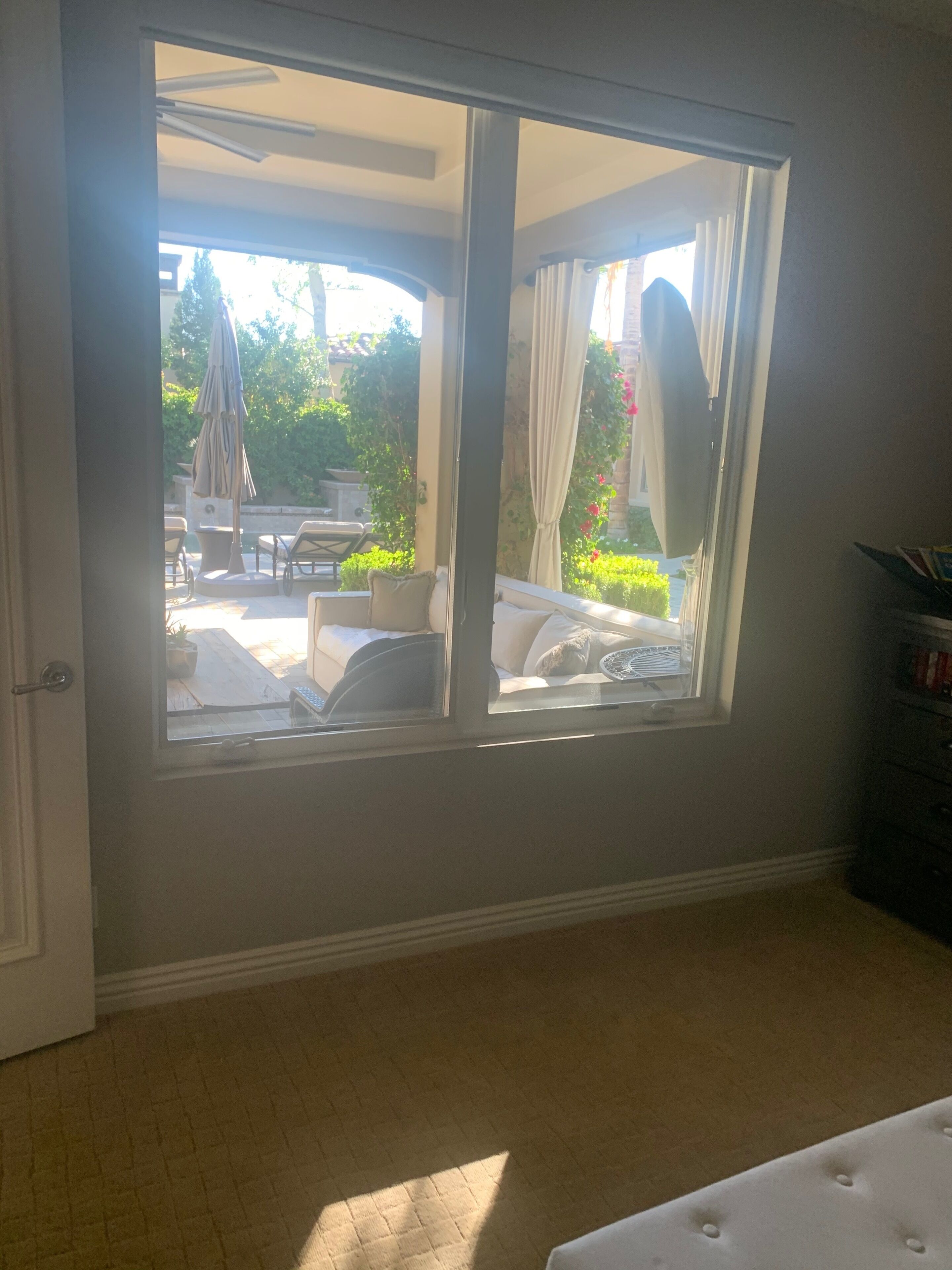 Une pièce dotée d’une porte-fenêtre coulissante donnant sur un patio extérieur aménagé avec une table et des chaises.