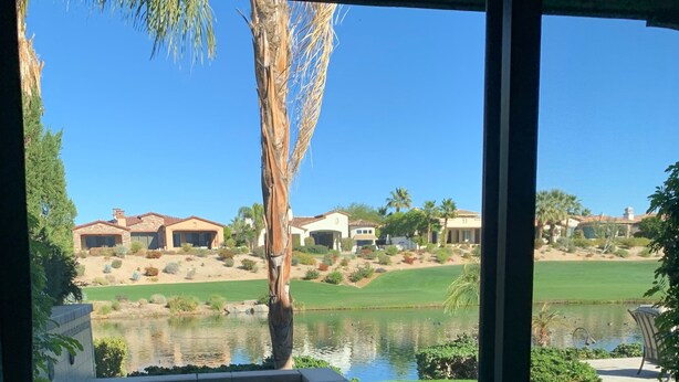 A patio with a view of a golf course, a swimming pool, and a palm tree. - Indian Wells Exclusive Home on Golf Course (Indian Wells)