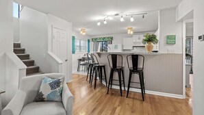 Une cuisine moderne dotée d’un îlot central, de tabourets de bar et d’un coin repas comprenant un canapé et des chaises.