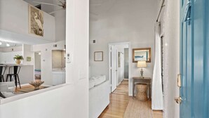 Un intérieur moderne comprenant une cuisine, un coin repas et un couloir menant à une chambre.