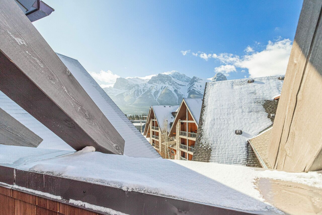 A snow-covered building with a modern architectural design, featuring triangular roofs and a view of snow-capped mountains in the background.