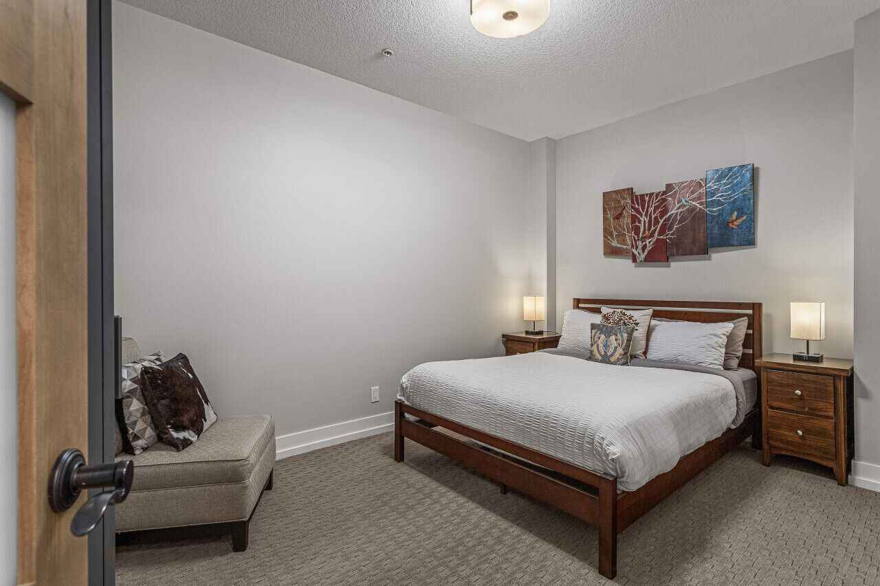 A bedroom with a wooden bed, bedside tables, a bench, and wall art.