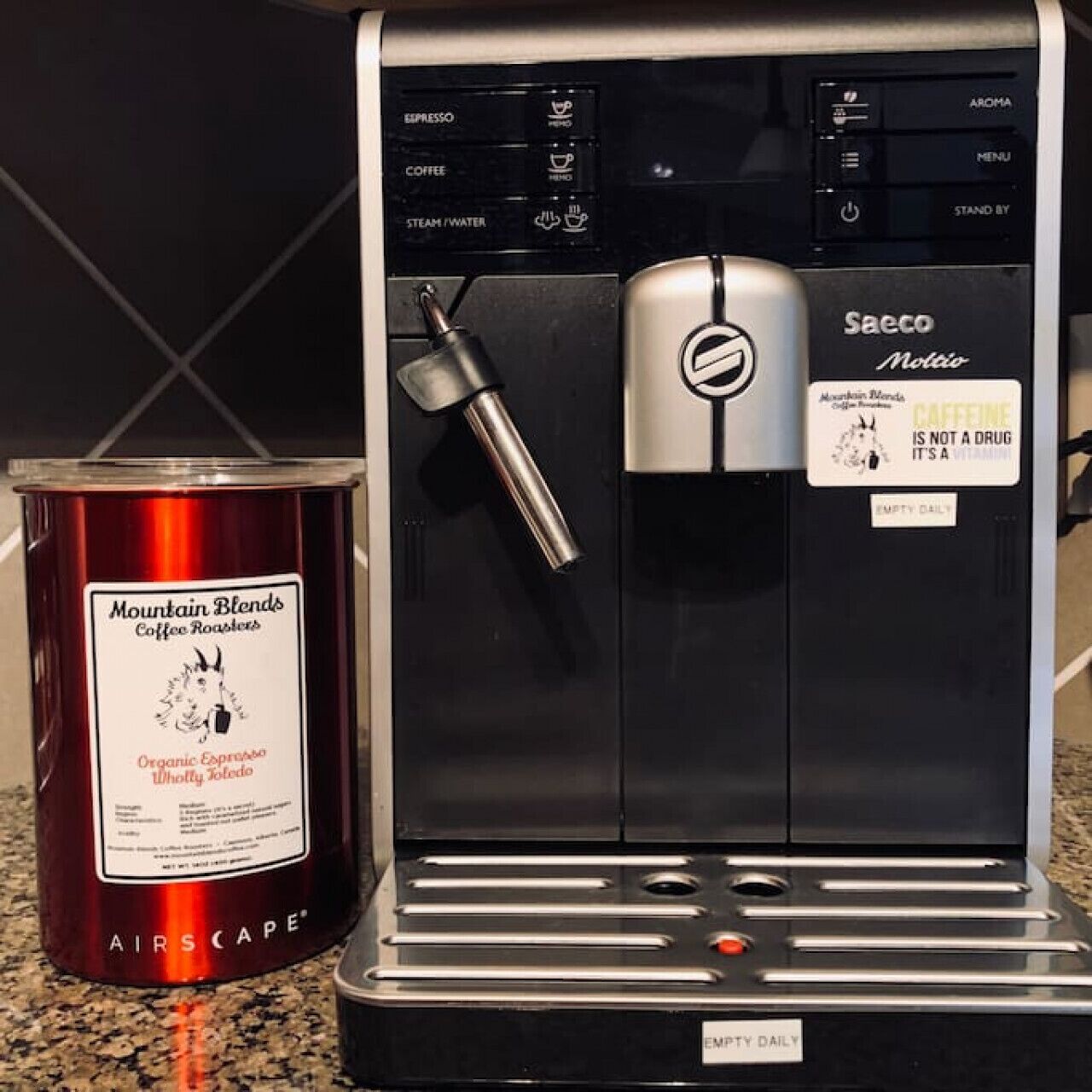 Een Saeco Melitta koffieapparaat met een blik koffie van Mountain Blends Coffee Roasters ernaast.