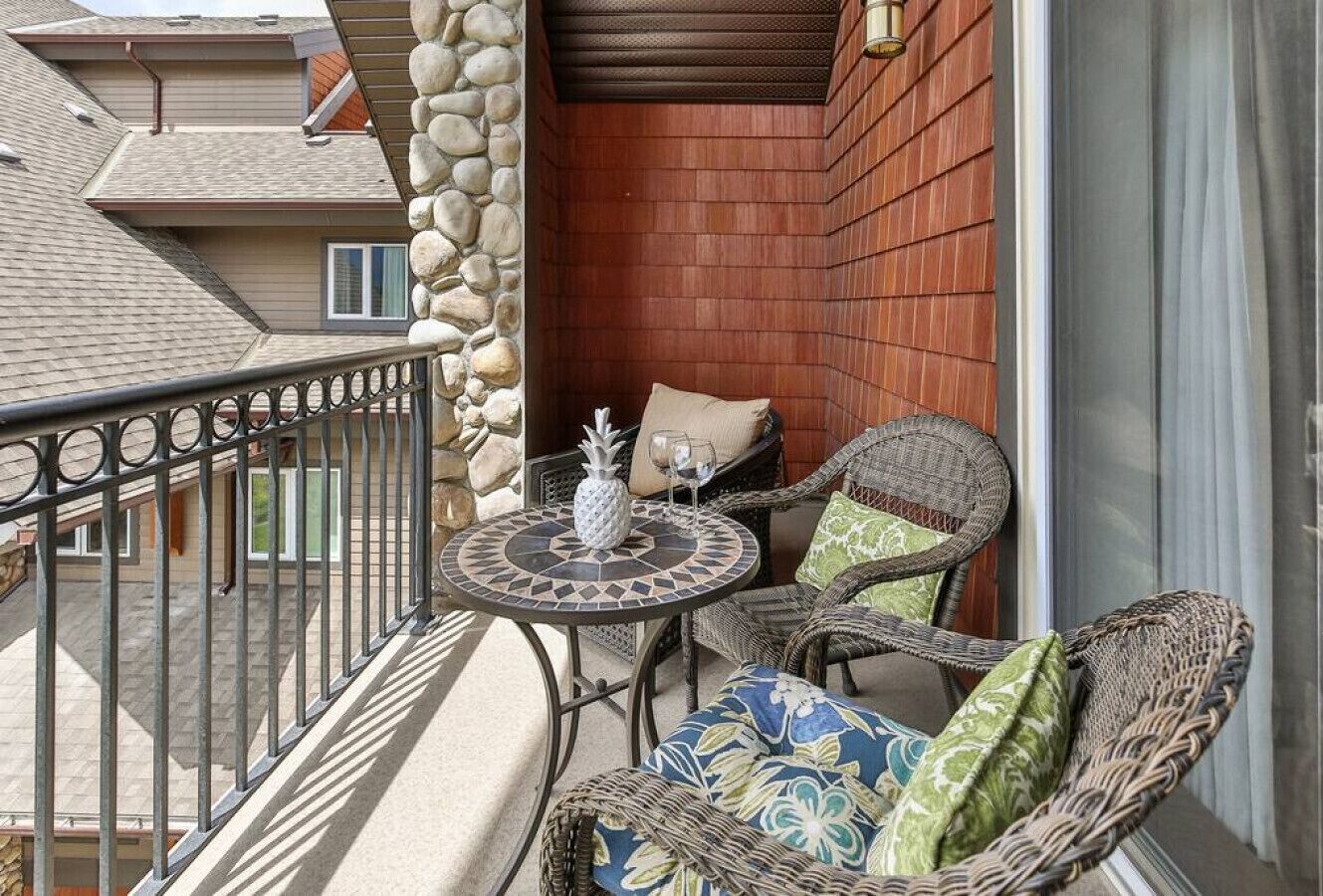 A balcony with wicker furniture, a small round table, and a stone wall.
