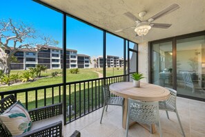 Enjoy a peaceful view from this balcony with a round table, two chairs, and a potted plant.