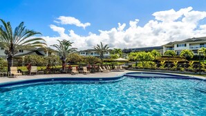 Une piscine entourée de bâtiments à plusieurs étages, avec des chaises longues et des palmiers.