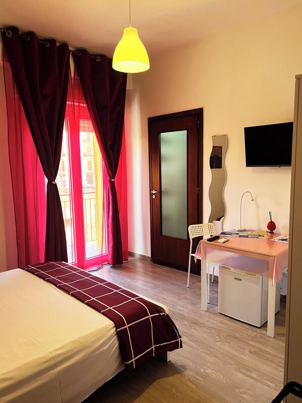 A bedroom with a bed, a desk, a chair, a TV, and a door. - B&B MaryJosè Trapani (Trapani)