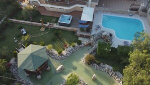 An aerial view of a resort with a swimming pool, hot tub, and a small building with a green roof. - Villa Omega Kefalonia (Karavados)
