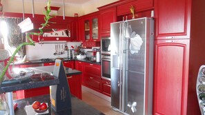 Una cocina con armarios rojos, electrodomésticos de acero inoxidable y encimera negra.