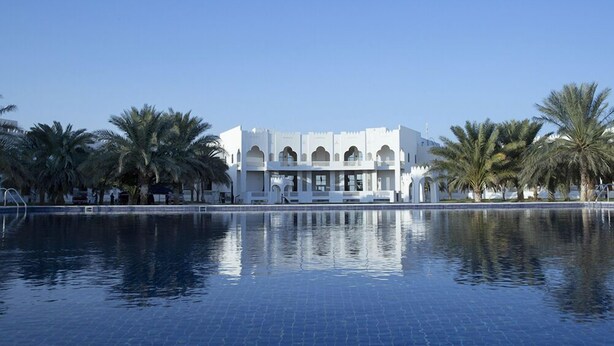 A large, white building with multiple arches and a pool in front. - Liwa Hotel Abu Dhabi (Mezaira'a)