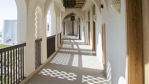 A corridor with arches, patterned floor tiles, and a wooden ceiling. - Liwa Hotel Abu Dhabi (Mezaira'a)