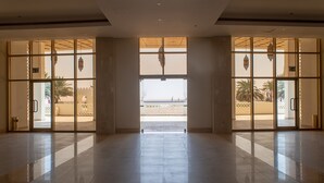 A spacious lobby with a view of the beach through large glass doors. - Liwa Hotel Abu Dhabi (Mezaira'a)