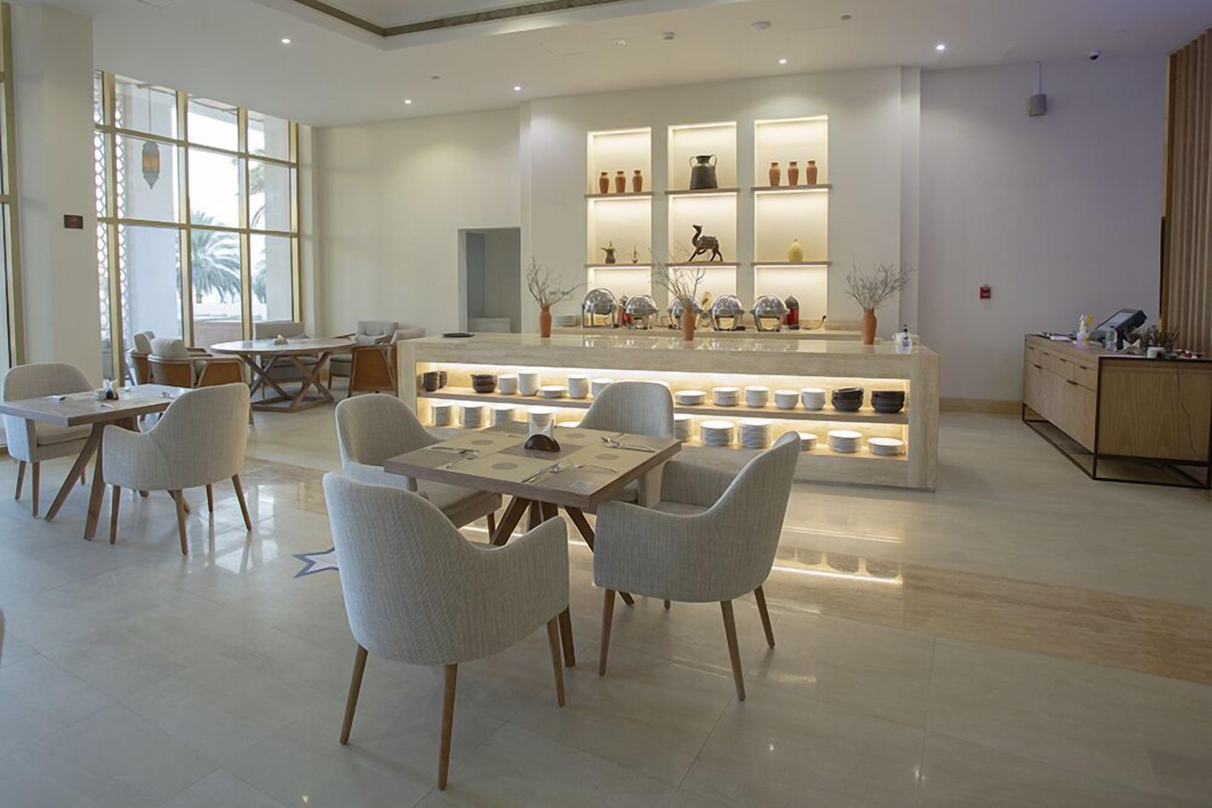 A modern hotel lobby with a central seating area, a reception desk, and a display of decorative items.