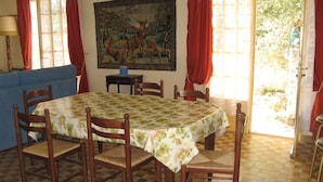 A dining room with a round table, six wooden chairs, a blue sofa, and a painting of deer on the wall. - Vacation home on the dune, directly on the beach, simple but ideal for the vacations (Hourtin)