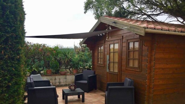 A wooden cabin with a patio area featuring outdoor furniture and potted plants. - Vacation home on the dune, directly on the beach, simple but ideal for the vacations (Hourtin)